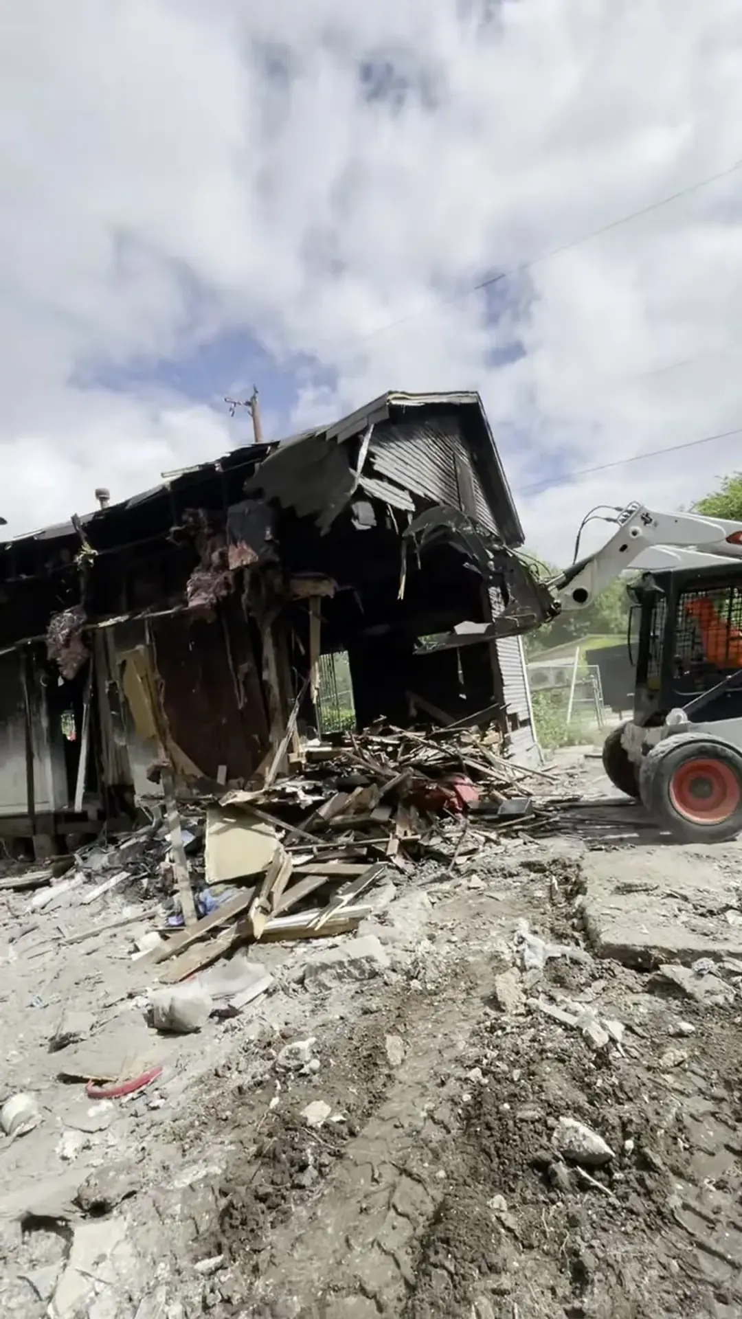 Five Star Trucking skid steer pushing in the wall of a fire-damaged house during a San Antonio demolition
