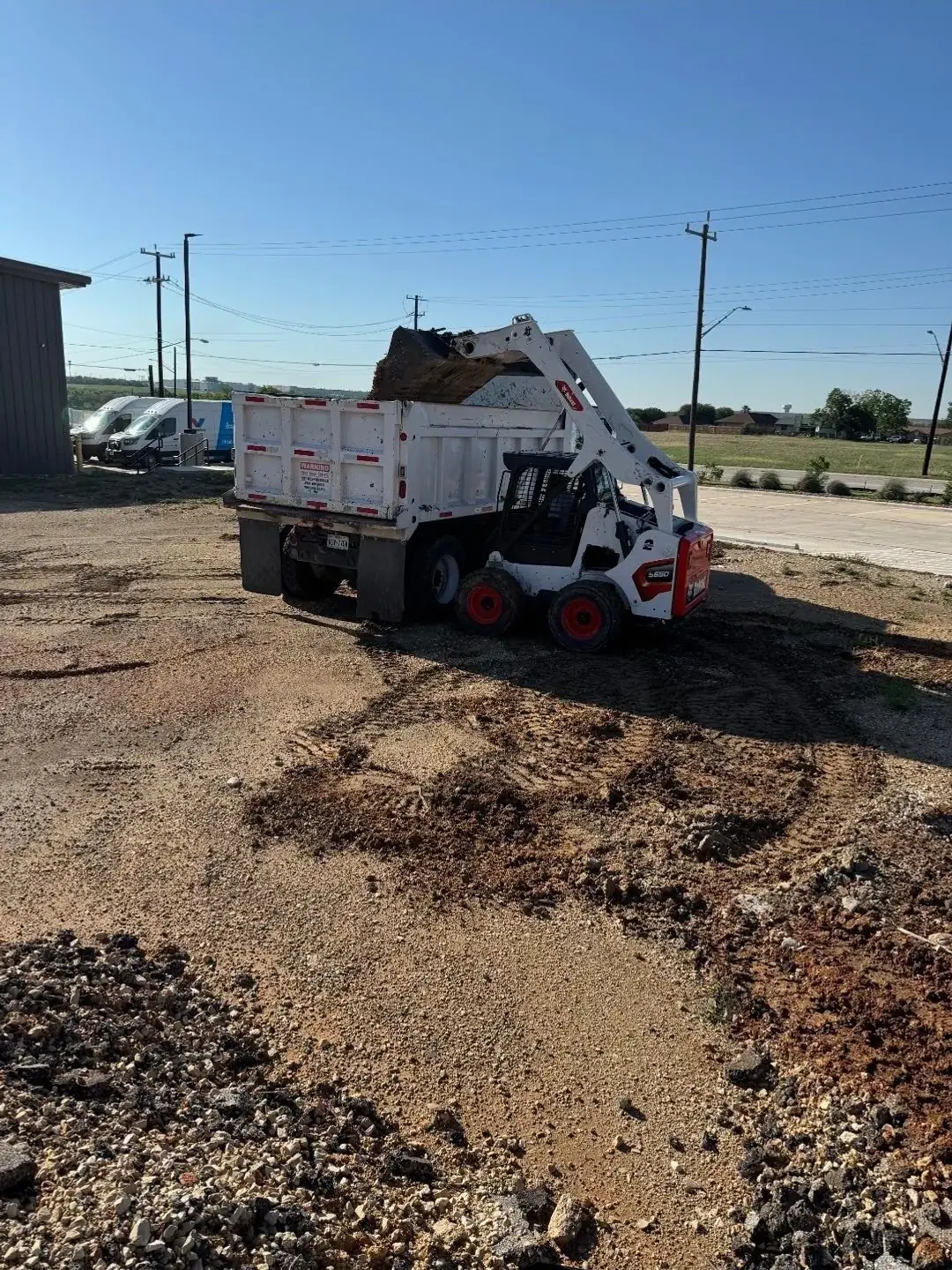 Five Star Trucking skid steer loading the company dump truck for haul-off